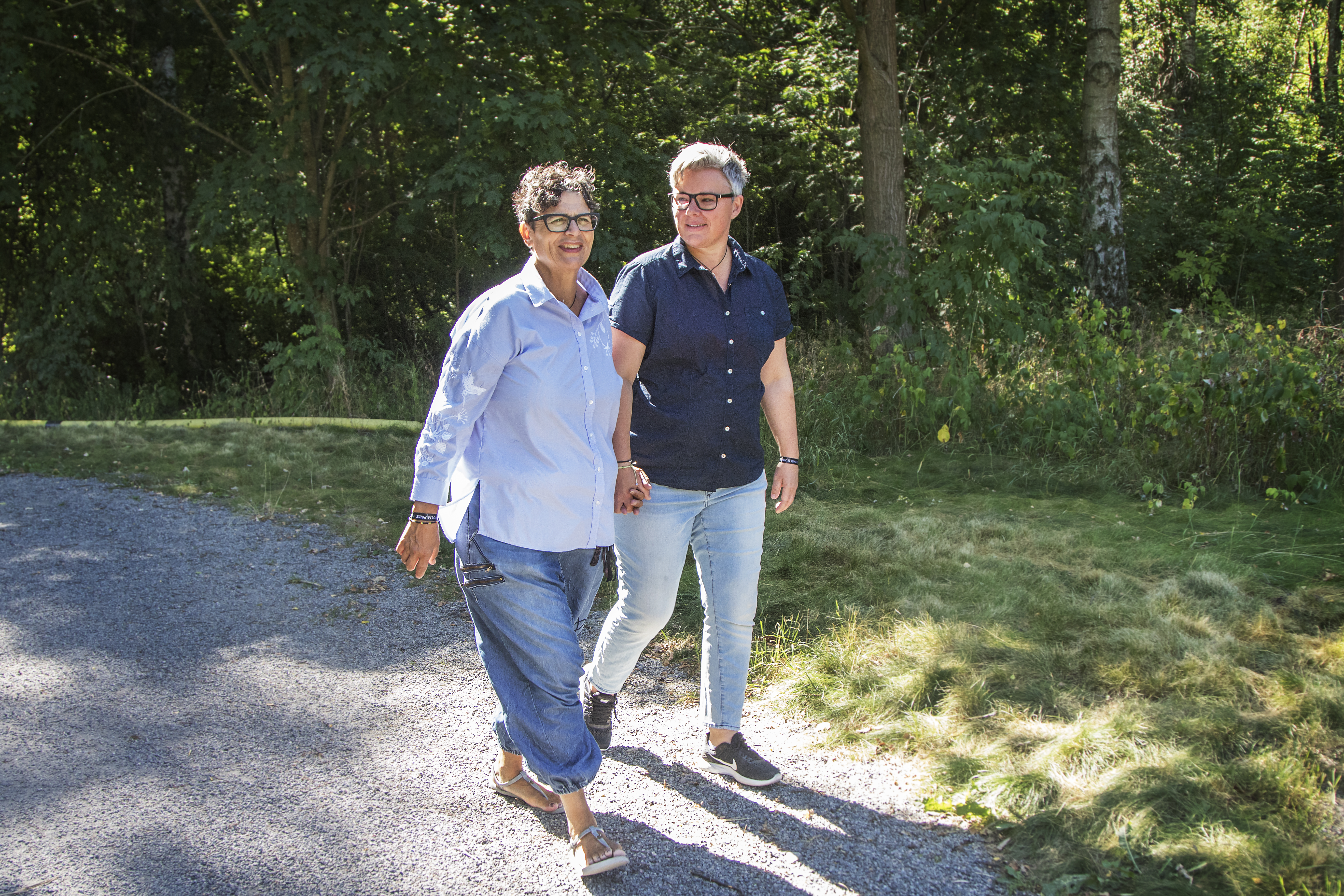 Två personer promenerar i en park i dagsljus.